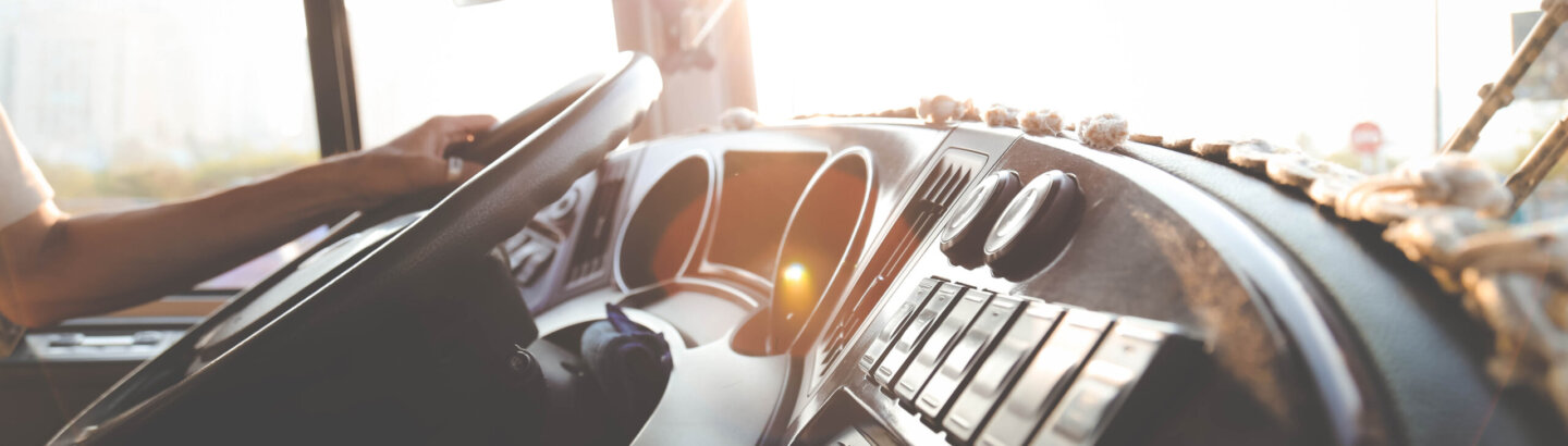 A close-up view of a truck deck with a man's hand holding the steering wheel