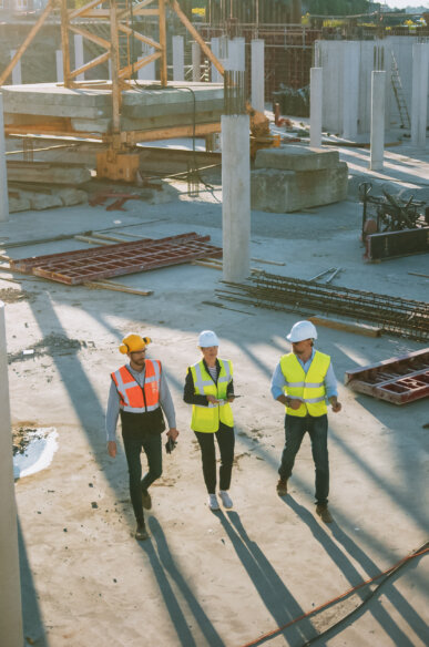 Three construction workers in safety gear walking through a building site