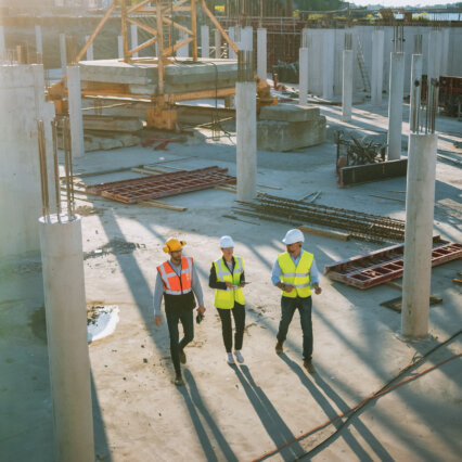 Three construction workers in safety gear walking through a building site